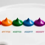 Neuf gouttes de peinture colorées avec leurs codes HEX alignées sur une palette blanche sous une lumière douce.