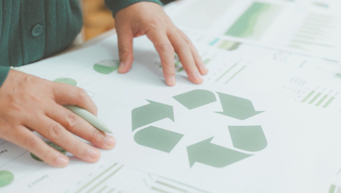 Personne tenant un symbole de recyclage avec graphiques verts sur bureau