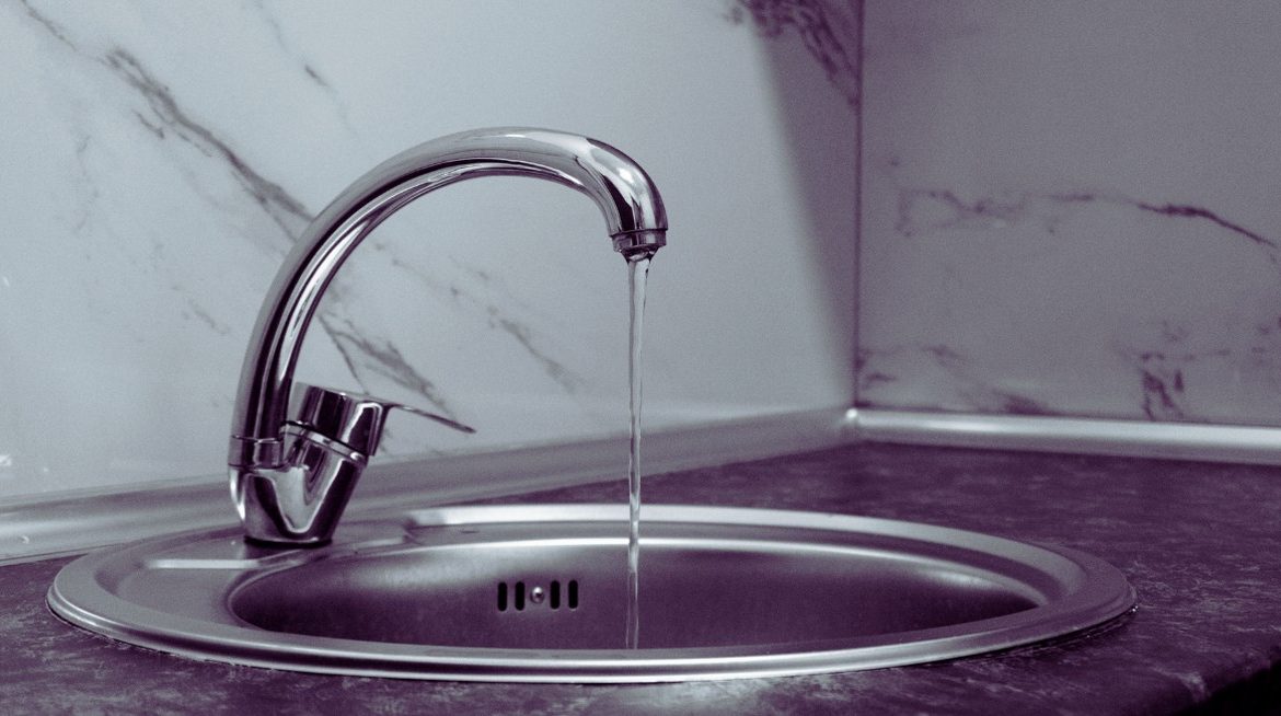Robinet de cuisine en chrome laissant couler un filet d eau dans un evier inox